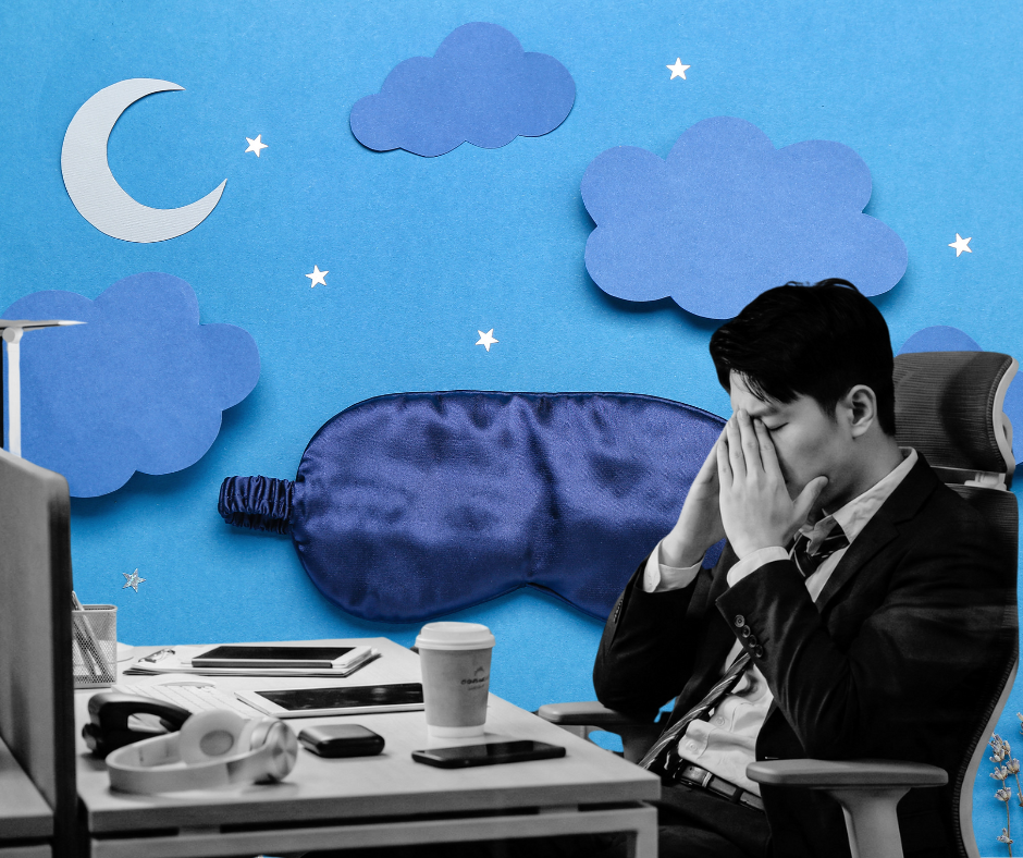 Office worker sitting at his desk, visibly tired and rubbing his eyes.